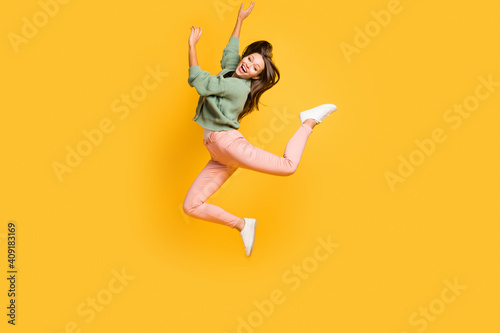 Full size photo of young happy positive good mood crazy girl jumping in victory isolated on yellow color background © deagreez