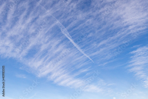 High white cirrus clouds with cirrostratus in a light blue sky with chaimtrails, sometimes called chair tails, indicate nice weather, but stormy changes occur within a few days. White clouds in a blue