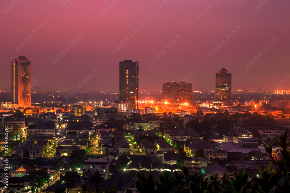 Fototapeta premium The high angle background of the city view with the secret light of the evening, blurring of night lights, showing the distribution of condominiums, dense homes in the capital community