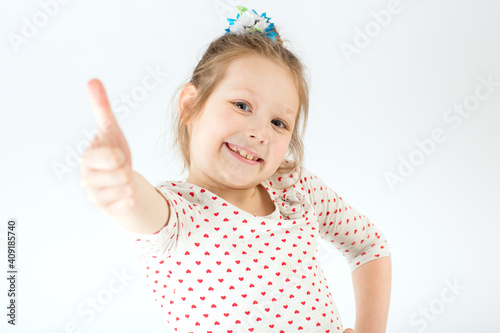 The girl stretches out her hand and shows her thumb up.