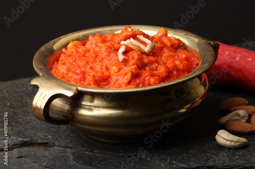 Gajar ka halwa is a carrot-based sweet dessert pudding from India. Garnished with Cashew almond nuts and Served in brass bowl.
