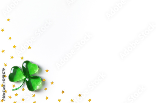 Konstfotografi Shamrock symbol made of green decorative glass hearts lying on white background with sparse gold stars confetti