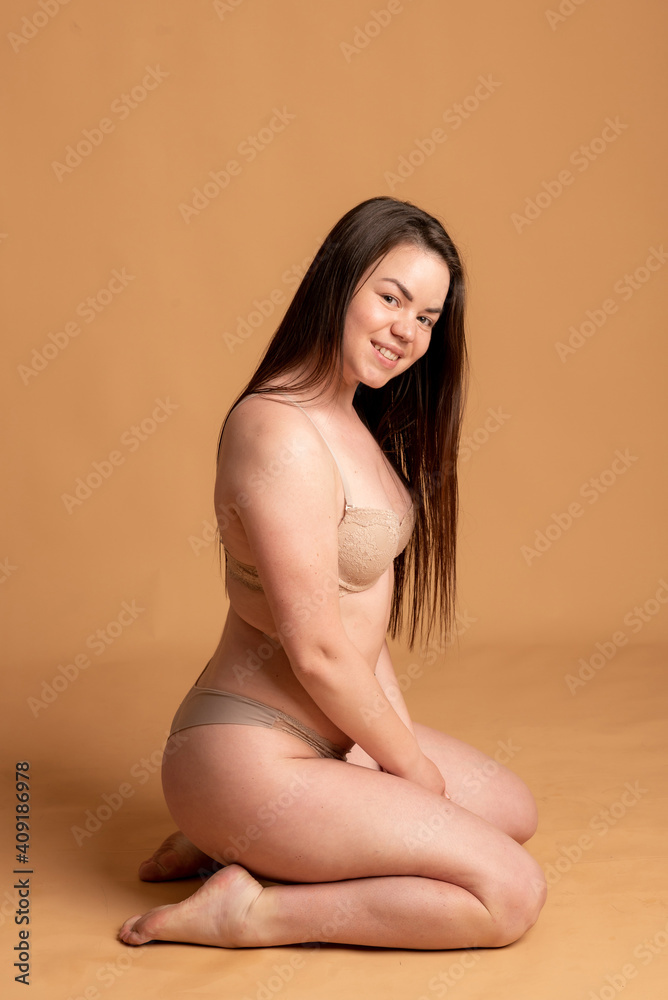 body positive. A girl in beige underwear poses on a pink background. body positive. A girl in beige underwear poses on a pink background.