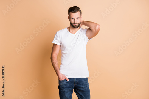 Photo of young handsome bristle man confident serious hand in pocket isolated over beige color background