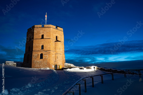 Gediminas Tower or Castle, the remaining part of the Upper Medieval Castle in Vilnius, Lithuania with Lithuanian flag in winter night with snow photo