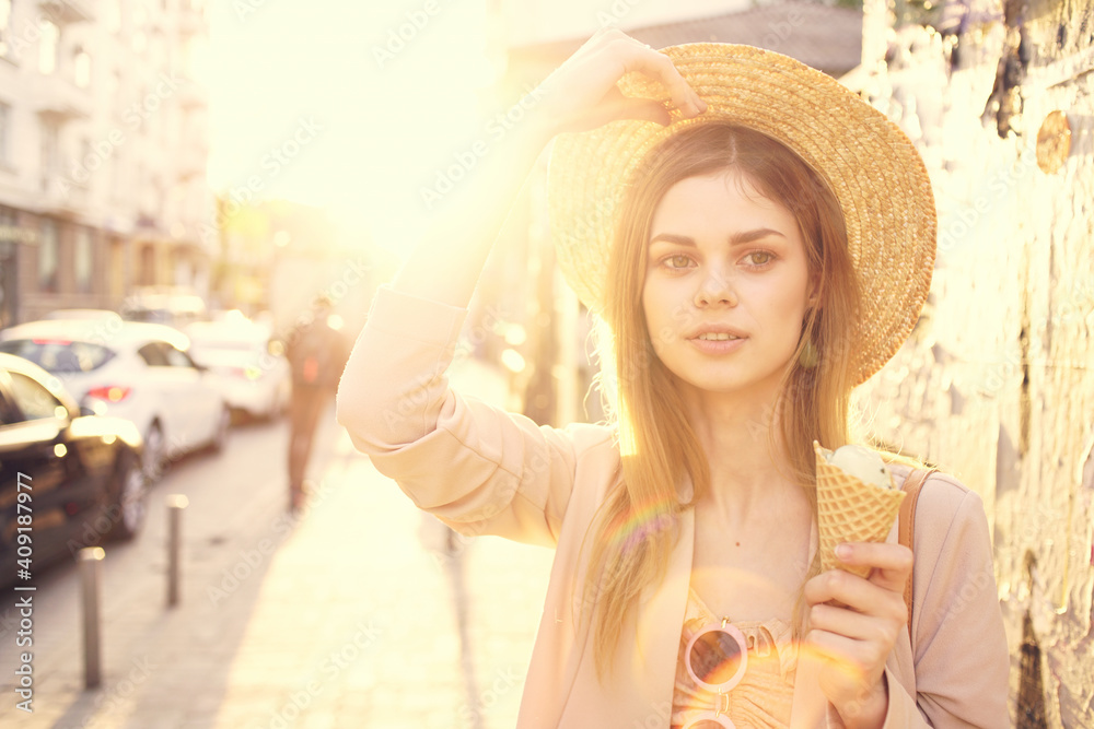 Woman in a hat with ice cream in hands outdoors in the city walk