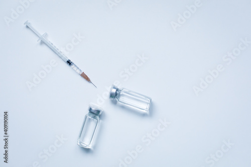 Two glass bottles with liquid and syringe on gray background with copy space. The medical conception of combating the covid-19 pandemic. Flu vaccination.  Flat lay