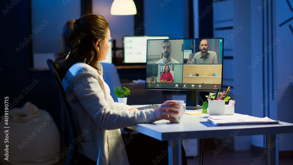 Naklejka premium Employee working overtime from business office late at night discussing with partners online using webcam. Corporate meeting using technology network wireless discussing on webcam late at night