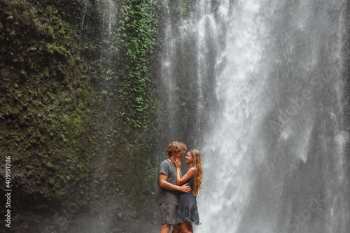 Young traveling couple explore waterfall in Bali  love story  people in love  vacation in Asia