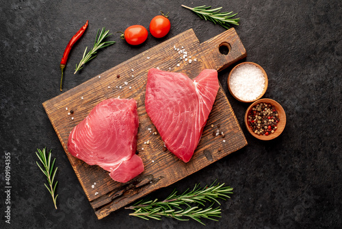Fotografia Fresh raw tuna steaks with rosemary and spices on a stone background