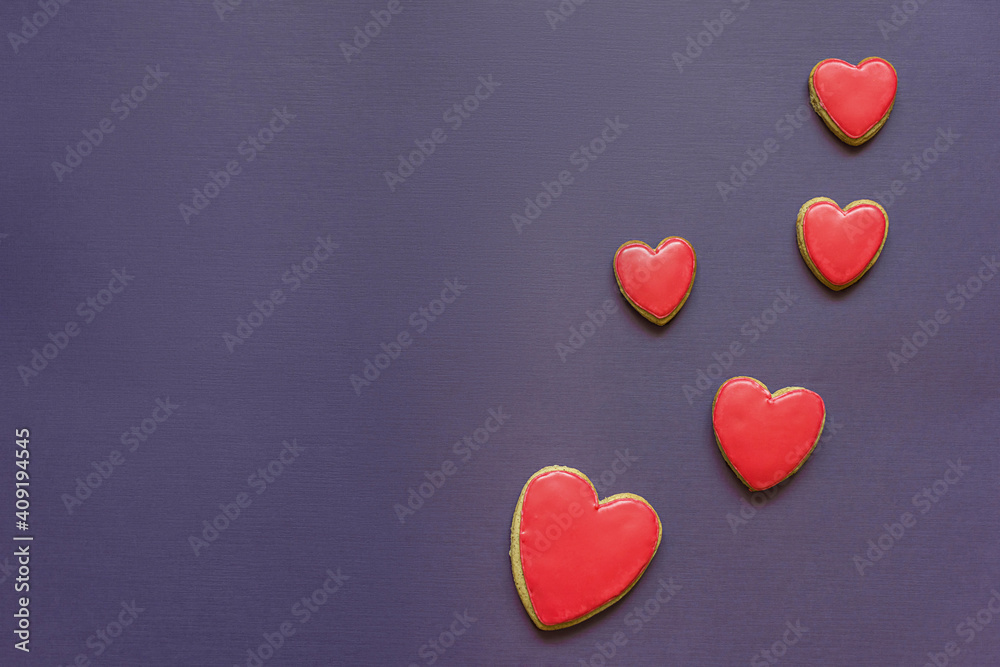 Valentine's Day, red heart shaped cookies on purple paper background on the right, flat lay. Love and Valentine's Day concept.