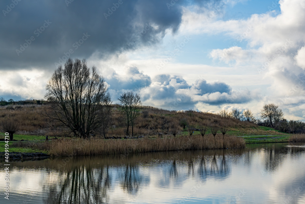 On this cold winter day with beautiful cloudy skies, the trees are reflected in the water of the canal behind the Buytenpark in Zoetermeer