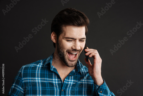 Excited handsome guy exclaiming and talking on cellphone