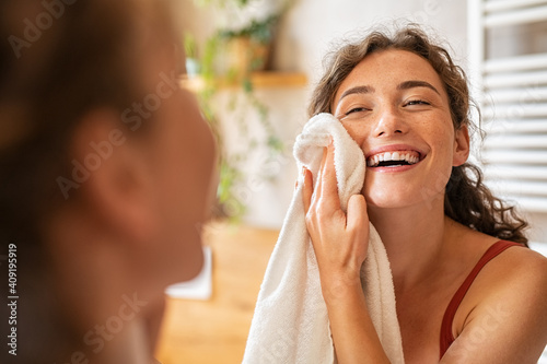 Happy woman wiping face with towel in bathroom