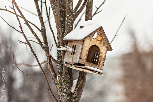 Beautiful wooden birdhouse for birds on a tree. Winter time