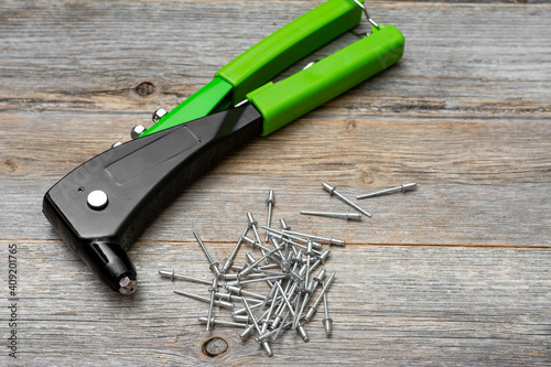 Rivet gun. A rivet gun on a gray wooden table in close-up. The rivet gun and rivets are on the desktop