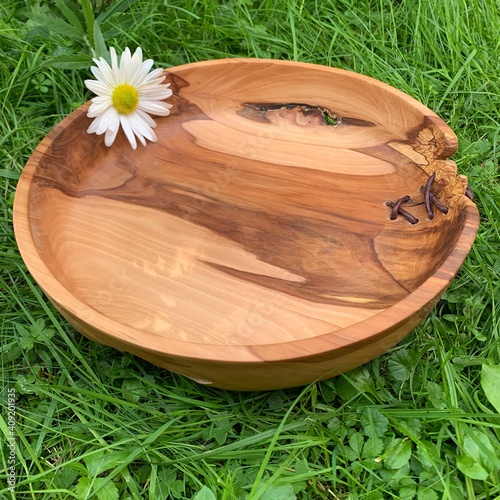 Schüssel aus Holz, mit Margerite, steht im Gras