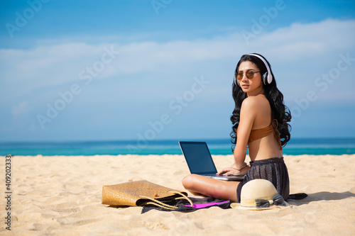 Young asia woman using a laptop computer on a beach. Freelance work concept and holiday working or money passive income