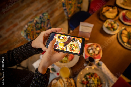 Woman hands taking picture, with smartphone, of the food served in the restaurant