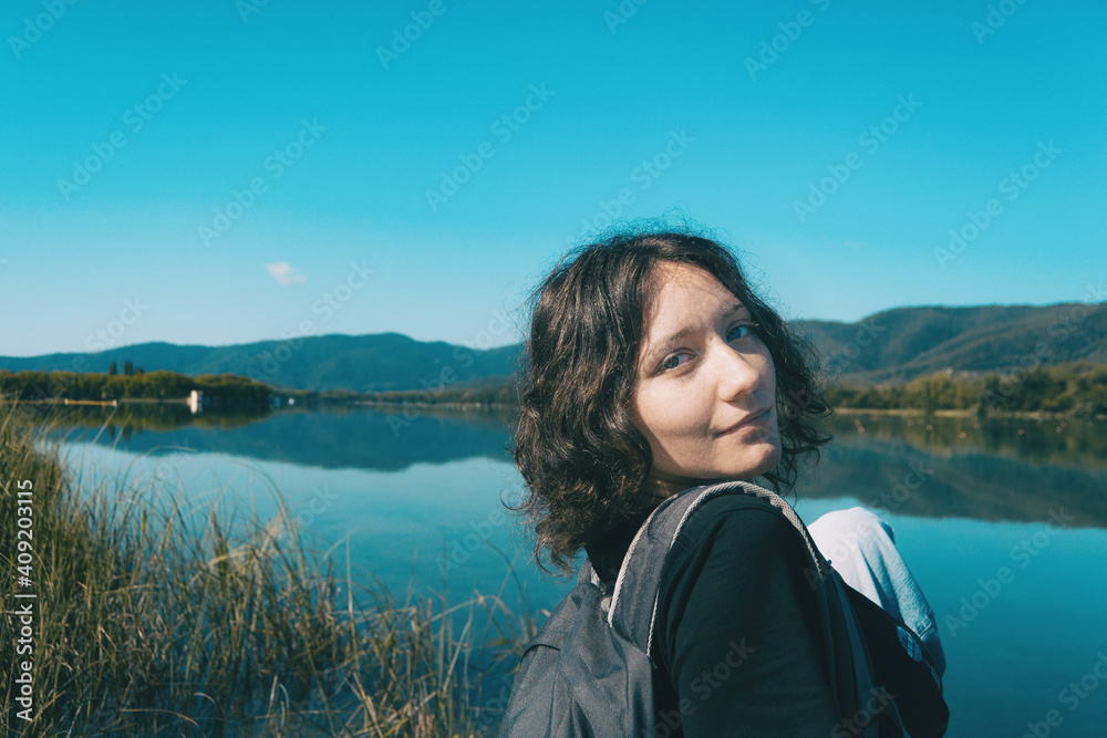 girl sitting on the edge of Banyoles lake with the landscape reflected in the water