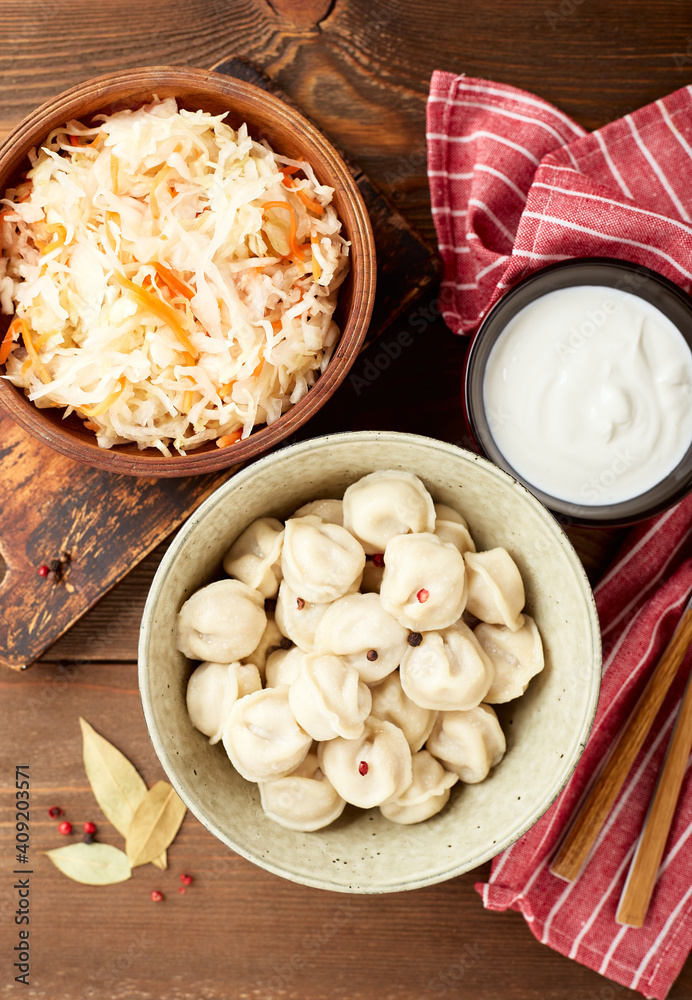 Dumplings stuffed with meat, pelmeni, ravioli, dumplings. Traditional homemade Russian pelmeni meat dumplings with sour cream over wooden background