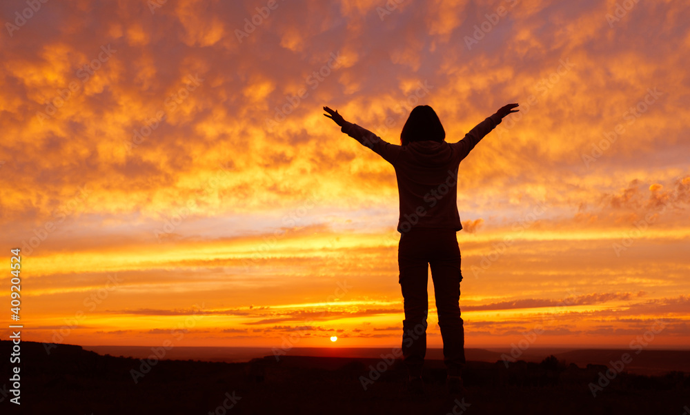Woman hiker with hands up arms during sunset. Silhouette of an unrecognizable female. Woman hiker with hands up arms during sunset. Silhouette of an unrecognizable female.