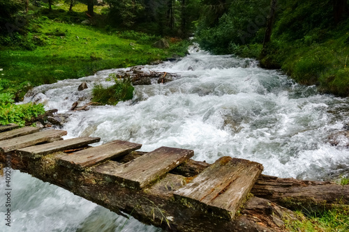 wooden brigdge over a rushing cold mountain creek while hiking photo