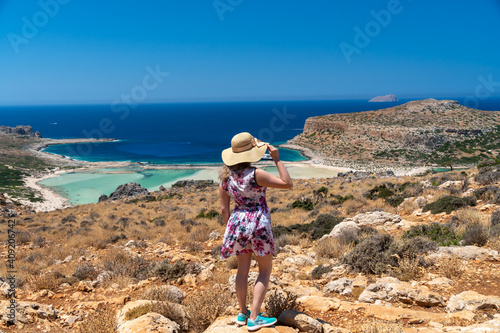 View of Balos Lagoon, Chania, with magical turquoise waters, lagoons, tropical beaches of pure whitesand and Gramvousa island on Crete, . Greece. Sexy girl with blond curly long hair and a cap posing
