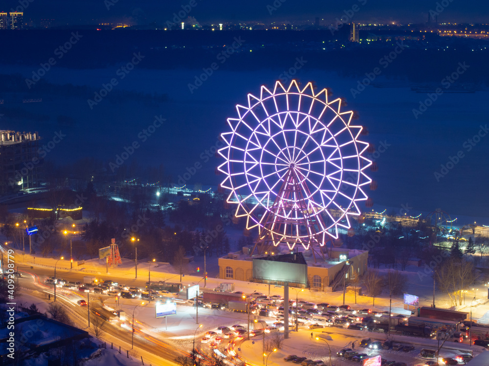 Ferris wheel on the Ob River embankment in Novosibirsk. High ferris wheel with beautiful illumination, working in winter in Novosibirsk at the river station.