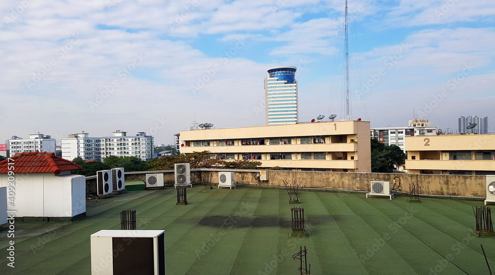 Fototapeta premium Many kind of air compressors installed on rooftop of terrace with height building, telecommunication tower, blue sky and clouds background. Technology and Exterior design.
