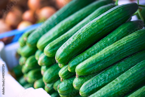 Fresh cucumbers lined up at an outdoor market by day 