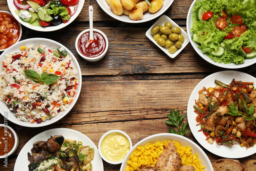 Buffet service. Frame of many different dishes on wooden table, space for text Buffet service. Frame of many different dishes on wooden table, space for text