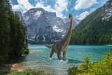 Brachiosaurus walks alone into cold lake before dinosaurs extinction. Snow on the mountains in the background.