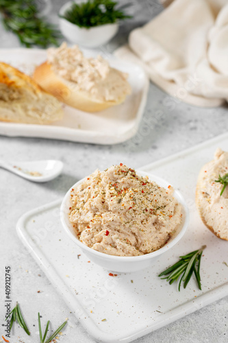 Chicken pate in a white bowl on a light gray kitchen table. Homemade chicken fillet pate with seasonings on a light background	
