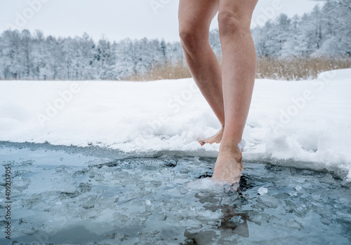 Платно Close up of female legs getting into ice cold water