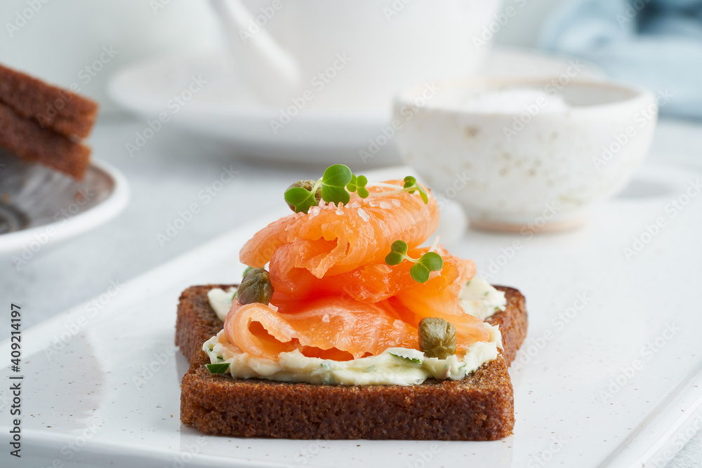 Smorrebrod - traditional Danish sandwiches. Black rye bread with salmon, cream cheese, capers on white background.