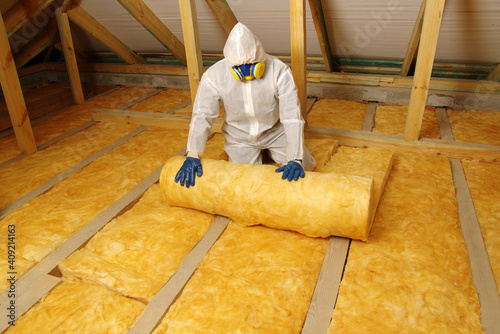 Foto Worker in protective respirator insulating glass wool insulation