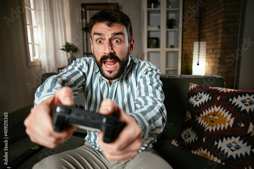 Young attractive man playing video games in the living room. Handsome man having fun at home. © JustLife