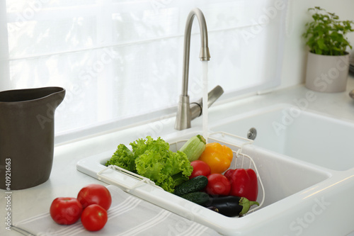 фотографія Many fresh ripe vegetables under tap water in kitchen sink