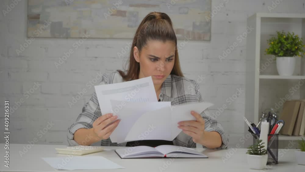 upset woman looking at papers with charts while sitting at workplace upset woman looking at papers with charts while sitting at workplace