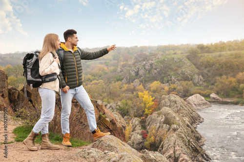 Couple of travelers with backpacks enjoying beautiful view near mountain river. Autumn vacation