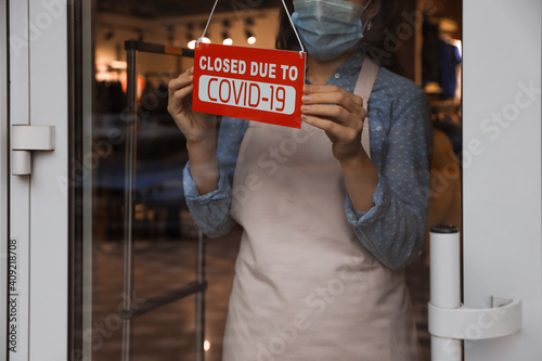 Woman in mask putting red sign with words 