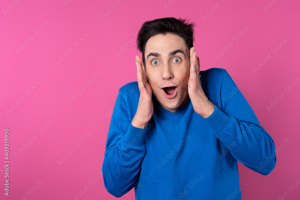 The young man is surprised. Pink background. Blue clothes. The young man is surprised. Pink background. Blue clothes.