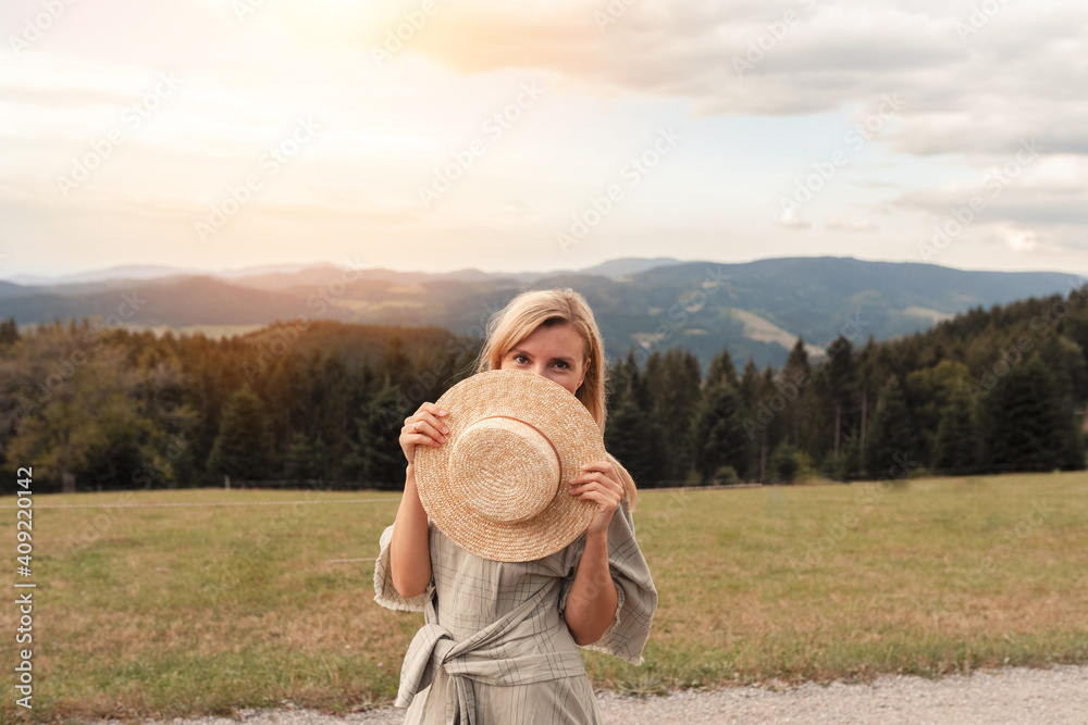 Beautiful happy young woman in a hat enjoing sunset in the mountains