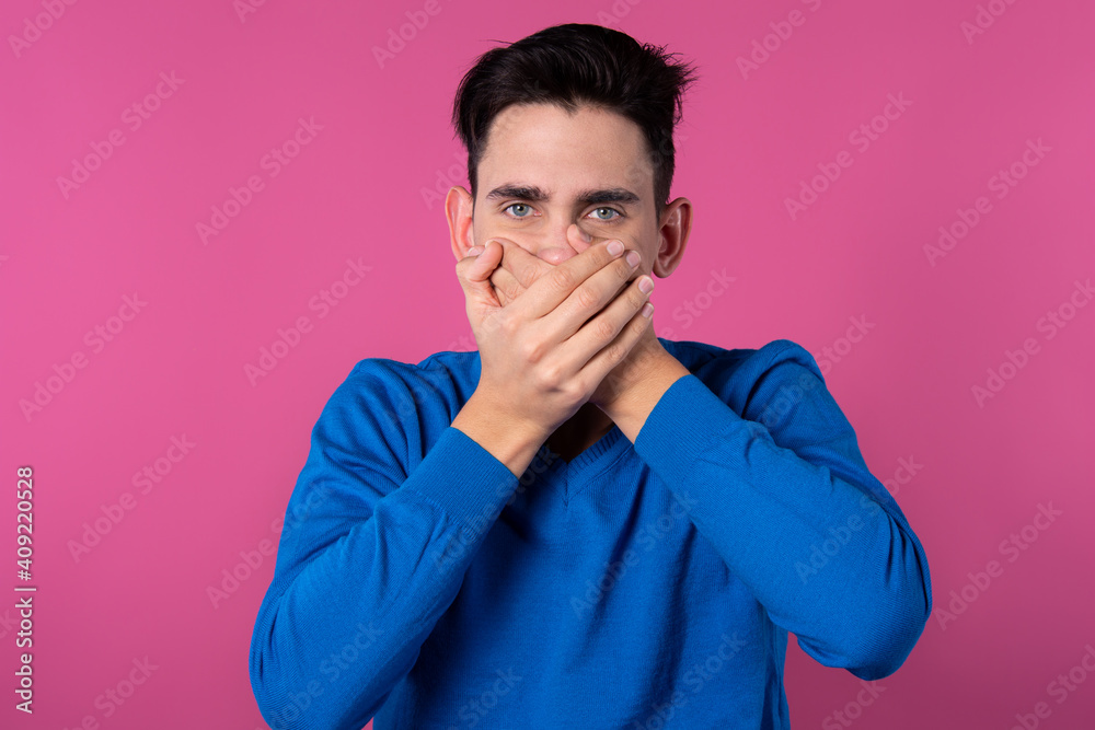 Fototapeta premium A young guy in a blue sweater. Don't speak evil. Do not listen to evil. Do not speak evil. Pink background.