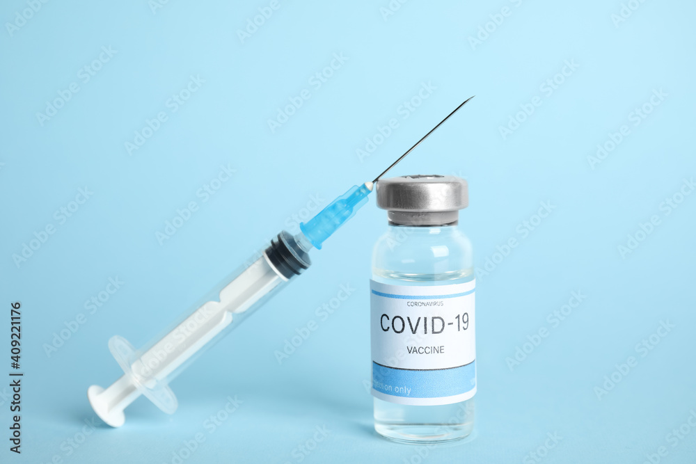 Vial with coronavirus vaccine and syringe on light blue background Vial with coronavirus vaccine and syringe on light blue background