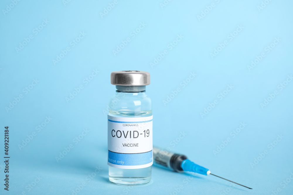 Vial with coronavirus vaccine and syringe on light blue background Vial with coronavirus vaccine and syringe on light blue background