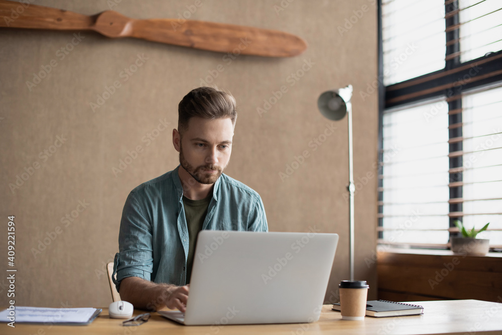 Fototapeta premium Young handsome man using laptop at modern office, Businessman or student working online on computer, Freelance, online marketing, distance education, e-learning, home work and lockdown concept.