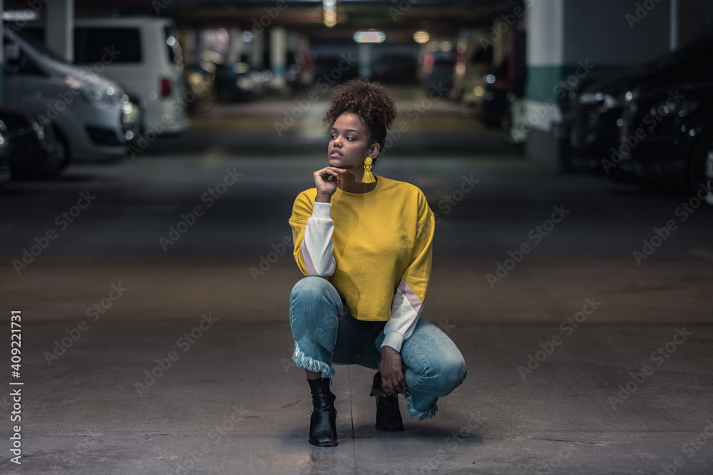 Thoughtful millennial black woman in trendy outfit in underground parking Thoughtful millennial black woman in trendy outfit in underground parking