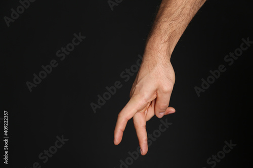 Man imitating walk with hand on black background, closeup. Finger gesture